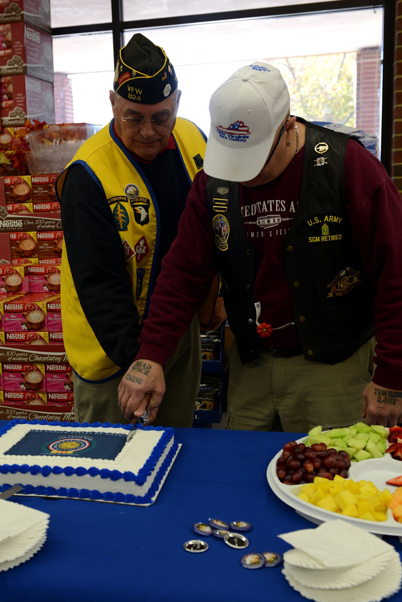 Retired U.S. Army Lt. Col. Jim Shamble, left, and retired Sgt. Maj. Timothy Pentecost, both members of Veterans of Foreign Wars Post 824, cut a cake at the conclusion of the 50th Anniversary Vietnam War Commemoration flag presentation ceremony at the Langley Air Force Base, Va., commissary, Nov. 9, 2013. Shamblem and Pentecost both served in the Vietnam War, and helped reveal the commemoration flag. (U.S. Air Force photo by Airman 1st Class Kimberly Nagle/Released)