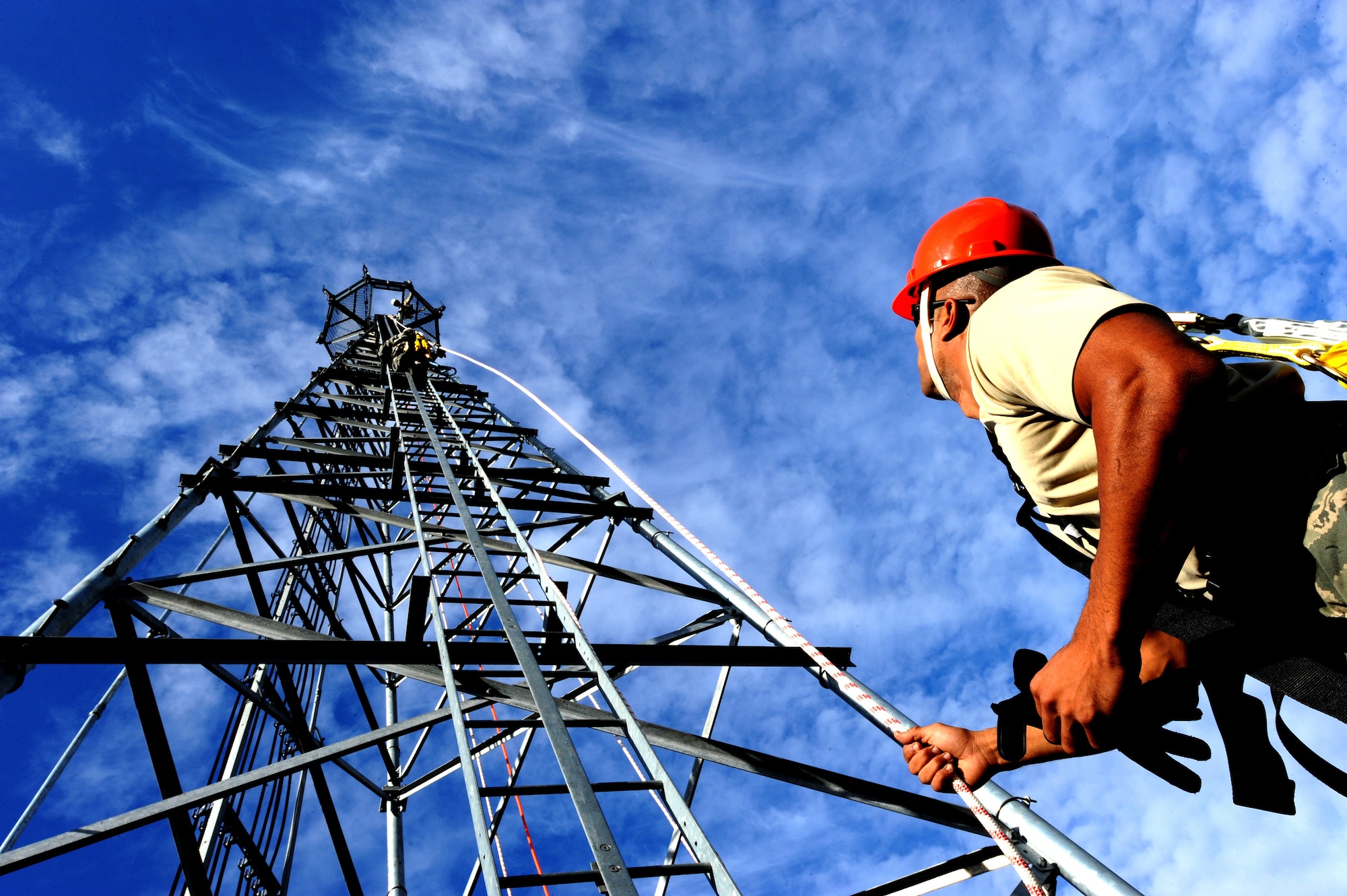 U.S. Air Force Staff Sgt. William Edwards, 4th Communications Squadron airfield systems technician, holds the safety rope as a crew member climbs a 100-foot tower at Seymour Johnson Air Force Base, N.C., Oct. 29, 2013. Airfield systems and ground radar technicians routinely climb towers to perform maintenance on equipment. (U.S. Air Force photo by Airman 1st Class Aaron J. Jenne)