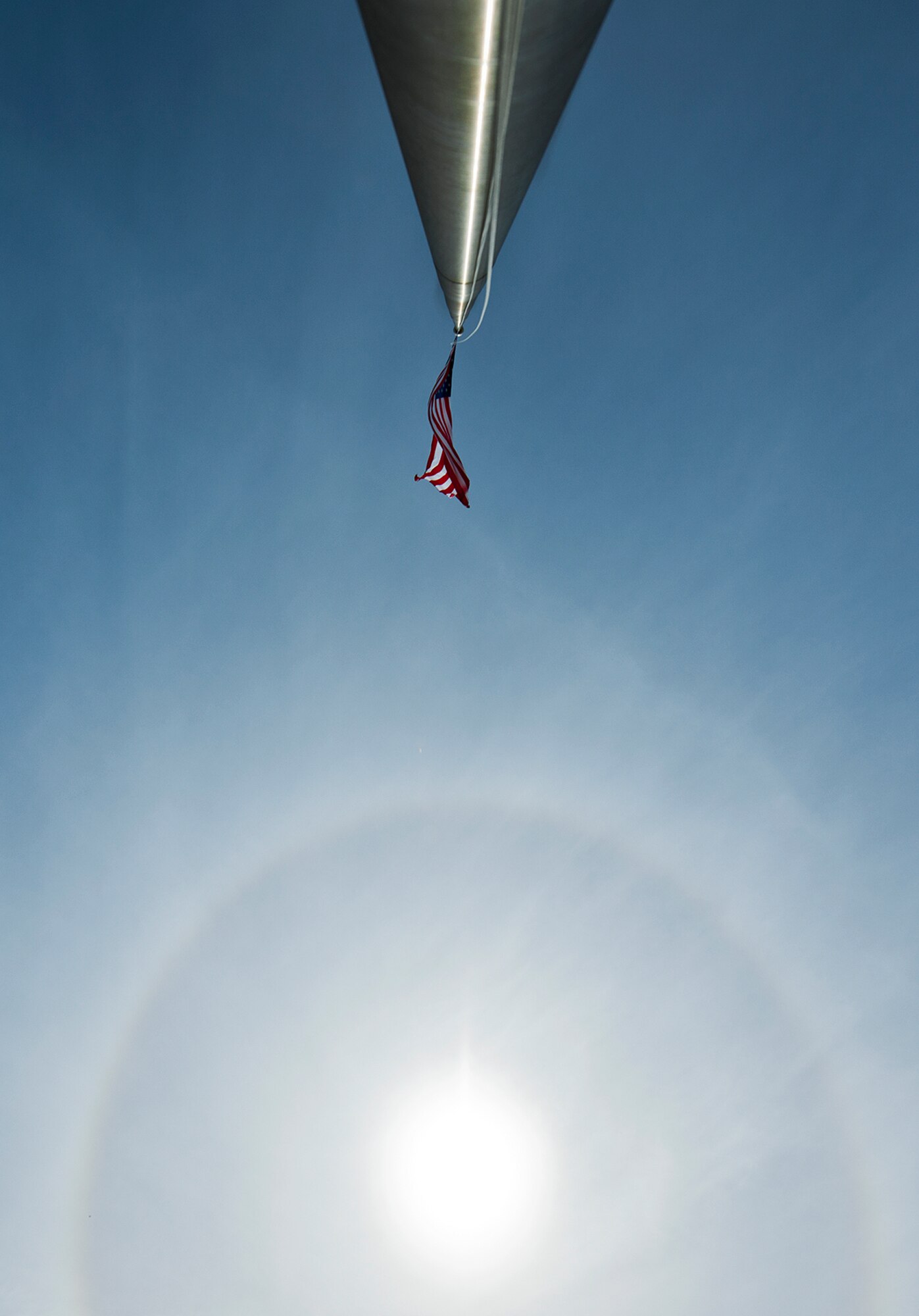 The American Flag flies below a giant solar halo in the sky over the Building 1 in the early afternoon Nov. 12 at Eglin Air Force Base, Fla. The optical phenomenon is caused by ice crystals in the atmosphere.  (U.S. Air Force photo/Samuel King Jr.)