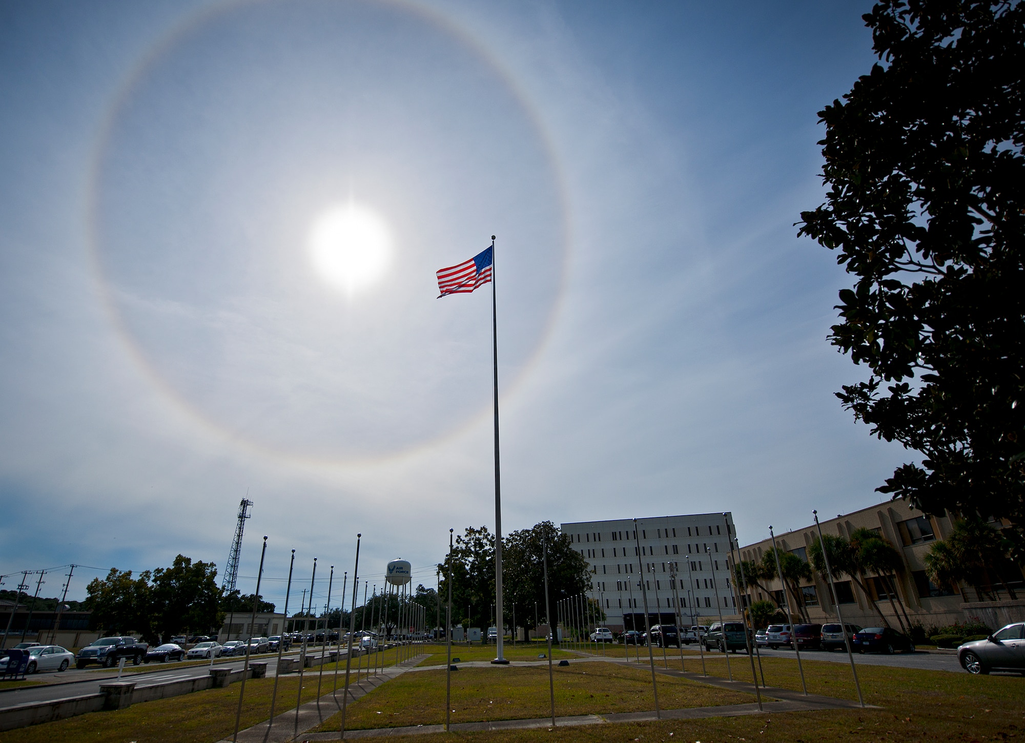 The American Flag flies below a giant solar halo in the sky over Building 1 in the early afternoon Nov. 12 at Eglin Air Force Base, Fla. The optical phenomenon is caused by ice crystals in the atmosphere.  (U.S. Air Force photo/Samuel King Jr.)