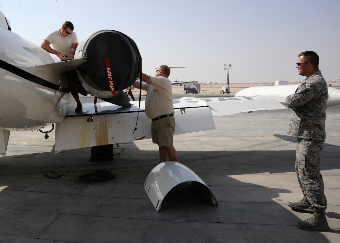 Tech. Sgt. Joseph Gatchell looks on as Warren Wiatrek and Cary Anderson perform maintenance on a C-21 Firebass at the 379th Air Expeditionary Wing in Southwest Asia, Nov. 5, 2013. The C-21s have a 10-man civilian contracted maintenance team responsible for getting the jets ready and dealing with all the regular maintenance schedules on top of generating sorties. Gatchell is the 379th Expeditionary Operations Group C-21 contracting officer representative deployed from Scott Air Force Base, Ill., and hails from League City, Texas. Anderson and Wiatrek are government contractors from Moorhead, Minn., and Colorado Springs, Colo., respectively. (U.S. Air Force photo/Senior Airman Bahja J. Jones) 