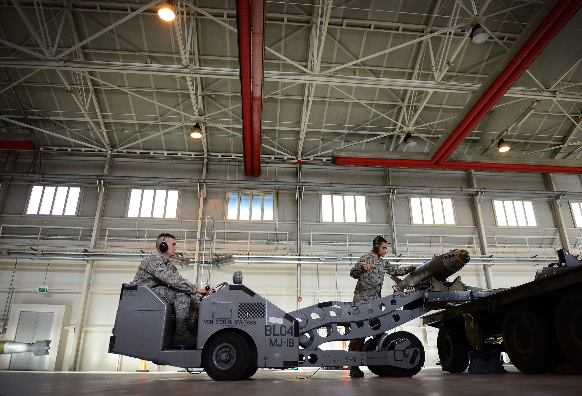 (From left) Airman 1st Class William Miller and Staff Sgt. Angelo Cepeda, 31st Aircraft Maintenance Squadron weapons load crew members, place an ordnance on a munitions rack, Nov. 6, 2013, at Aviano Air Base, Italy. The 31st Munitions Squadron weapons load crew members are responsible for loading and unloading munitions. (U.S. Air Force photo/Senior Airman Matthew Lotz)