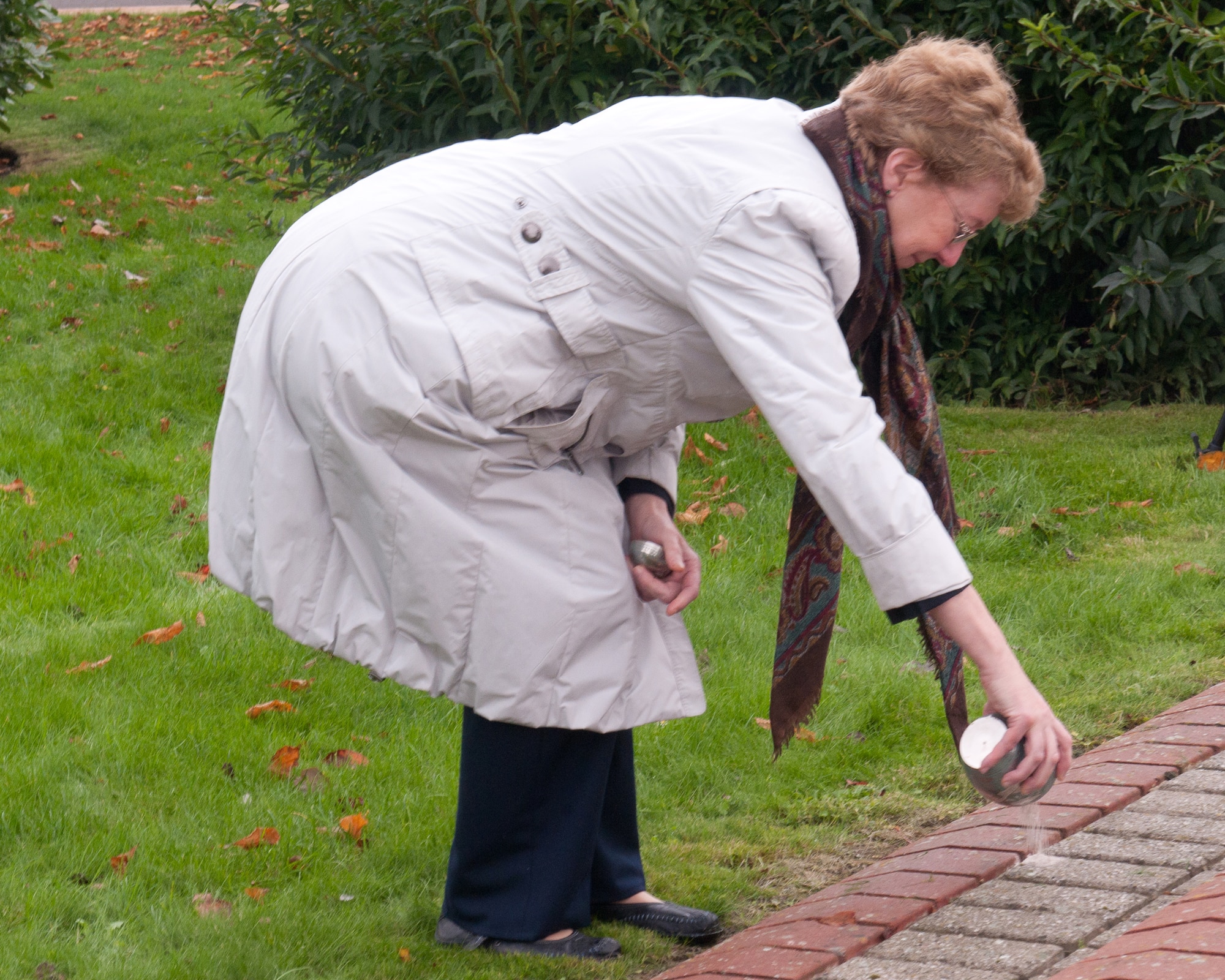 RAF ALCONBURY, United Kingdom – Emily Lewney spreads her father’s ashes at the RAF Alconbury flagpoles Oct. 26. Retired Tech. Sgt. Emil Dihlmann served at RAF Alconbury from 1943 to 1945 and he had such fond memories of his time there that his family asked if they could spread his ashes on the base. (U.S. Air Force photo by Staff Sgt. Brian Stives)