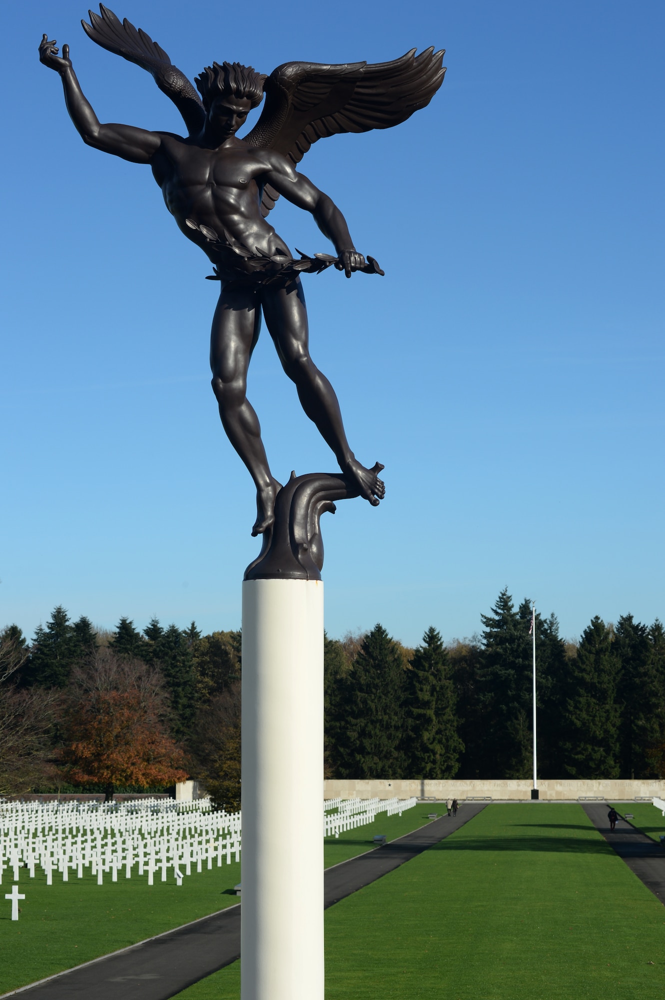 HOMBOURG, Belgium --- A guardian angel statue stands before a grass field in front on an American Flag at the Henri-Chapelle American Cemetery Nov. 11, 2013. More than 40 American service members gathered at the cemetery for a Veterans Day memorial service. (U.S. Air Force photo by Staff Sgt. Joe W. McFadden/Released)