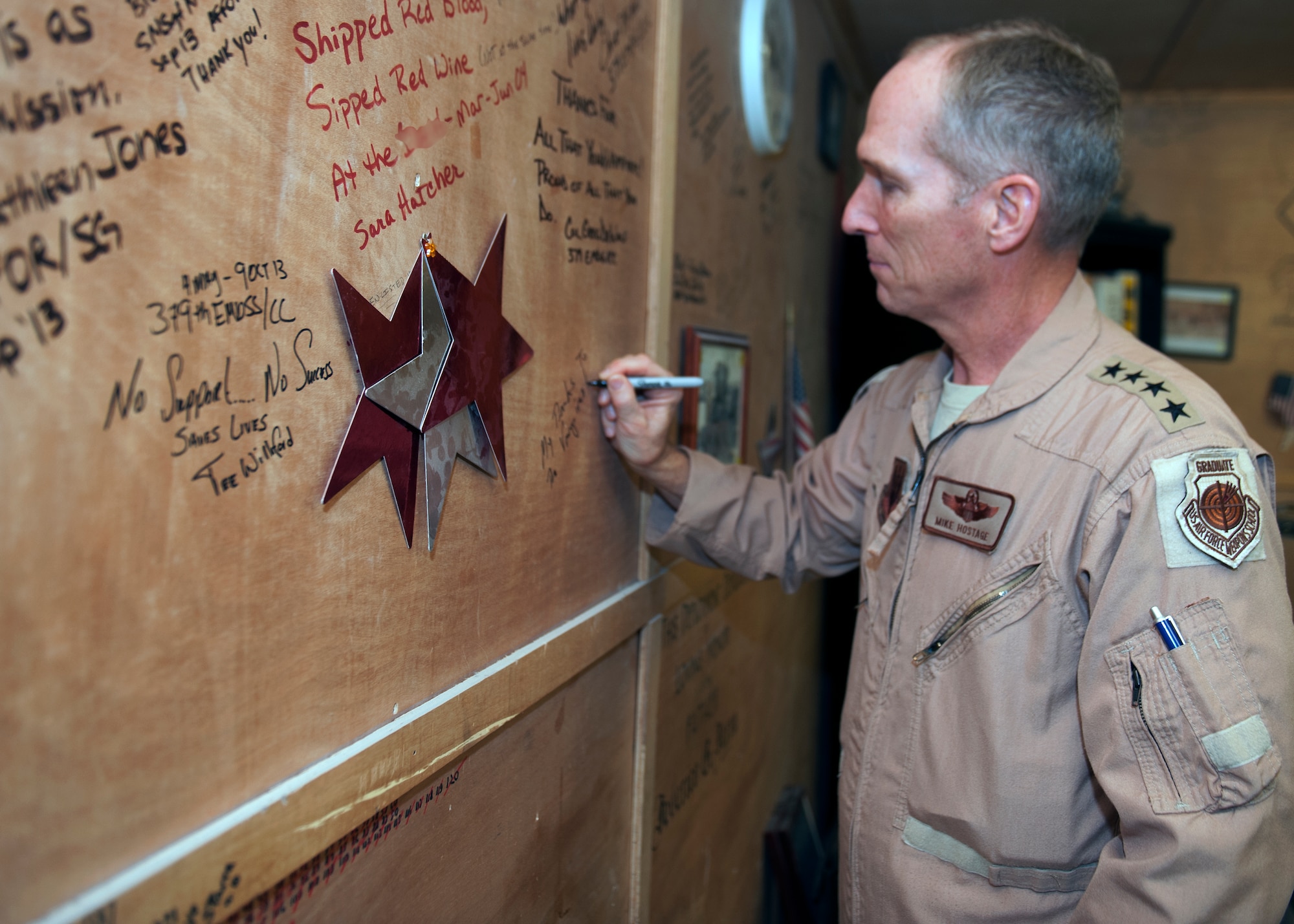 Gen. Mike Hostage signs a wall in the Blood Transshipment Center at the 379th Air Expeditionary Wing in Southwest Asia, Nov. 11, 2013. Distinguished visitors are invited to sign the BTC’s “wall-of-fame” after receiving a mission brief. During his immersion, Hostage visited the Airman and Family Readiness Center, the BTC and the 71st Expeditionary Air Control Squadron. Hostage is the commander of Air Combat Command. (U.S Air Force photo/Senior Airman Bahja J. Jones) 