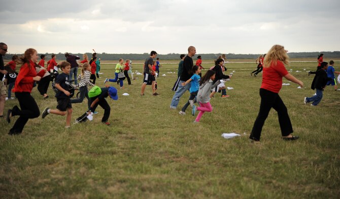 Children rush through a field picking up candy dropped from a vintage C-47 Skytrain Nov. 9, 2013, near the South Texas Regional Airport, Hondo, Texas. Retired Col. Gail Halvorsen re-enacted a candy drop known as Operation Little Vittles, a 15-month humanitarian mission that took place during the Berlin Airlift in 1948.