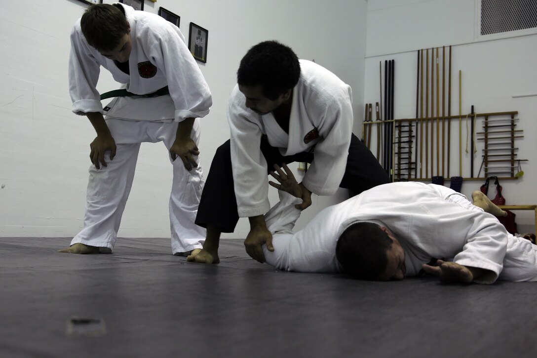 Xavier Turcotte, a Jujitsu instructor, teaches Gregg Pierson, a Jujitsu student, how to apply a submission hold to Nick Dowden, a Jujitsu student, during a class at building 39, next to the Goettge Memorial Field House, aboard Marine Corps Base Camp Lejeune, Nov. 7. Classes are held Tuesdays and Thursdays from 6:30 p.m. to 9 p.m.