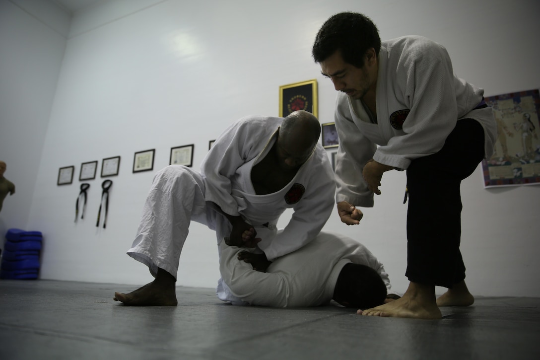 Xavier Turcotte, a Jujitsu instructor, teaches Donald Hatch, a Jujitsu student, how to apply a submission hold to Nick Dowden, a Jujitsu student, during a class at building 39, next to the Goettge Memorial Field House, aboard Marine Corps Base Camp Lejeune, Nov. 7. Classes are held Tuesdays and Thursdays from 6:30 p.m. to 9 p.m.