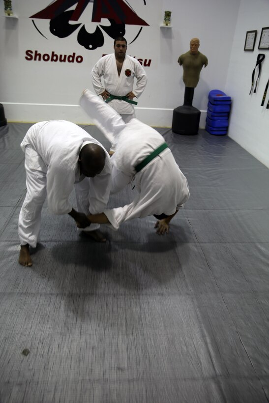 Nick Dowden, a Jujitsu student, watches Donald Hatch flip Gregg Pierson, Jujitsu students, during a class at building 39, next to the Goettge Memorial Field House, aboard Marine Corps Base Camp Lejeune, Nov. 7. Classes are held Tuesdays and Thursdays from 6:30 p.m. to 9 p.m.