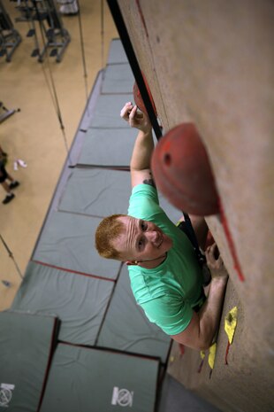 Sgt. Matthew S. Davies, a 26th Marine Expeditionary Unit radio operator, reaches for a hold on the rock wall at the Wallace Creek Fitness Center aboard Marine Corps Base Camp Lejeune, Nov. 12. The indoor rock wall stands 35 ft. tall and has 15 separate belay lines to ensure climber safety.