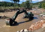 The Texas Army National Guard's 36th Infantry Division's Domestic All-Hazards Response Team-West continues to coordinate assistance requests and support for the Colorado flood relief effort. Pictured here, a military hydraulic excavator works to clear the remainder of a Colorado road after a flood washed it away.