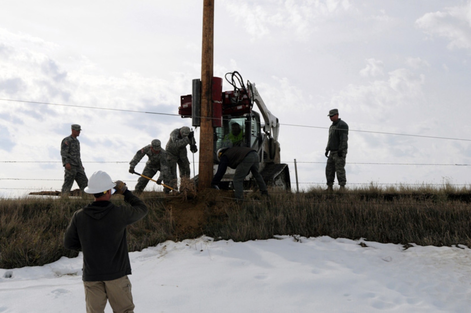 South Dakota National Guard Soldiers assist an electrical crew with setting a utility pole along a rural road near Faith, S.D., Oct. 10, 2013, to help restore power to residents. About 50 South Dakota National Guard members were called to state active duty to support local citizens during the aftermath of an Oct. 4 winter storm that crippled western South Dakota and left tens of thousands without electricity.