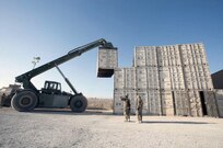 South Dakota Army National Guard Staff Sgt. Adam Holen, 152nd Combat Sustainment Support Battalion, of Volga, S.D., operates a rough terrain container handler with guidance from two Soldiers from the Maryland Army National Guard's 1129th Transportation Company, at Kandahar Airfield, Afghanistan, Oct. 8, 2013.