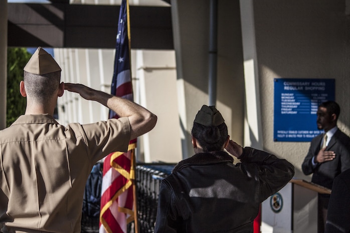 Lt. David Hammond, a station chaplain and Maj. Elizabeth Pham, executive officer of Headquarters and Headquarters Squadron, salute the United States flag during the playing of the National Anthem as part of a Veterans Day memorial ceremony that took place in front of the Commissary aboard Marine Corps Air Station Iwakuni, Japan, Nov. 8, 2013. The ceremony included several guest speakers and a cake-cutting ceremony.