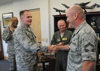 Col. Johnny Roscoe, 15th Wing commander, congratulates Senior Master Sgt. Todd Larsen, 747th Communications Squadron flight chief, for his selection to chief master sergeant this week, as Chief Master Sgt. Leslie Bramlett, 15th Wing command chief, and Col. Terry Scott, 15th Wing vice commander, applaud his accomplishment, at the 15th Wing headquarters building, at Joint Base Pearl Harbor-Hickam, Hawaii.  (U.S. Air Force photo/Tech. Sgt. Jerome S. Tayborn)