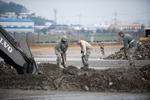 Staff Sgt. Jerrel Washington, Senior Airman Rezeq Khalifeh and Staff Sgt. Richard Simmons, 8th Civil Engineer Squadron, clear leftover dirt during a combined Airfield Damage Repair Exercise at Kunsan Air Base, Republic of Korea, Nov. 14, 2013. The exercise with ROK air force's 1st Civil Engineer Squadron allowed members of both air forces to work together, learn different methods and become more proficient with airfield repairs. (U.S. Air Force photo by Senior Airman Clayton Lenhardt/Released)