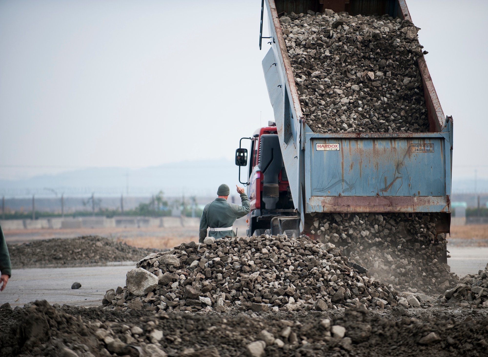Staff Sgt. Richard Simmons, 8th Civil Engineer Squadron, signals to a truck driver during a combined Airfield Damage Repair Exercise at Kunsan Air Base, Republic of Korea, Nov. 14, 2013. The exercise with ROK air force's 1st Civil Engineer Squadron allowed members of both air forces to work together, learn different methods and become more proficient with airfield repairs. (U.S. Air Force photo by Senior Airman Clayton Lenhardt/Released)