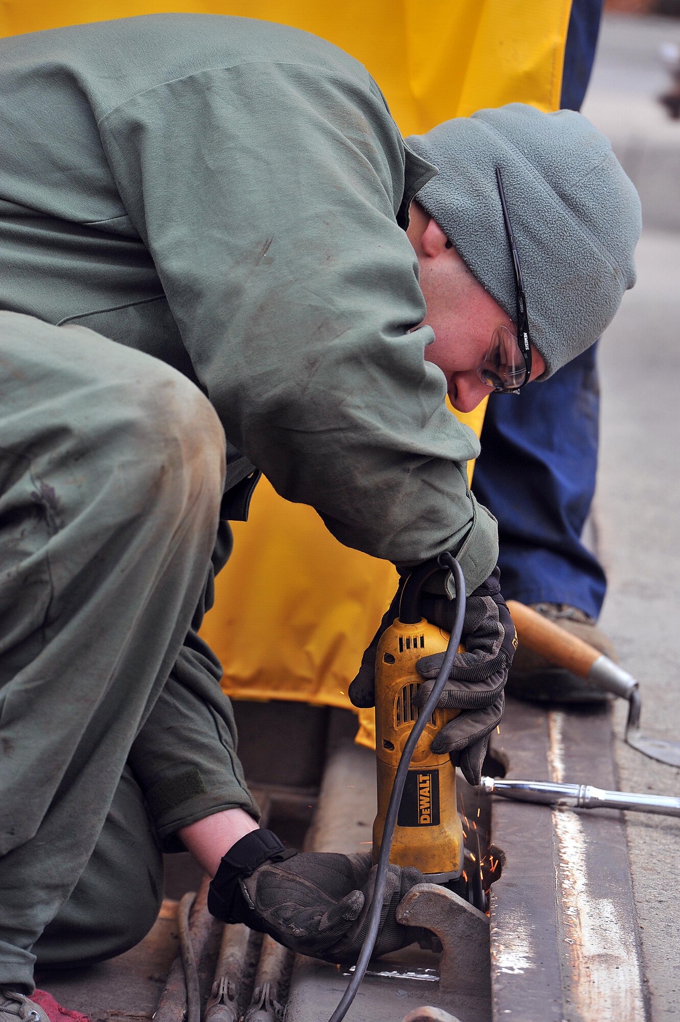 Senior Airman Christian Acosta, 92nd Civil Engineer Squadron structure shop, grinds medal by the front gate Nov. 13, 2013, at Fairchild Air Force Base, Wash. The pop-up barriers require maintenance at least once a year. (U.S. Air Force photo by Staff Sgt. Veronica Montes)