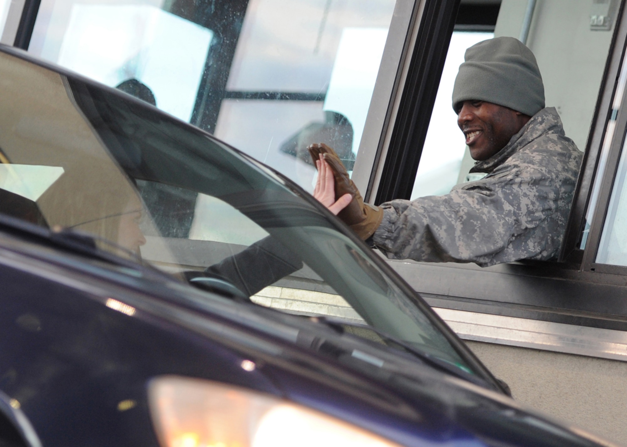 Spc. Adrian Hooks, a native of Indianapolis, Ind., assigned to 164th Military Police Company, part of U.S. Army Alaska's 2nd Engineer Brigade, gives a high-five and a smile to a visitor after checking her I.D. card at the Government Hill gate on Joint Base Elmendorf-Richardson, Alaska, Nov. 13, 2013. (U.S. Air Force photo/Justin Connaher)