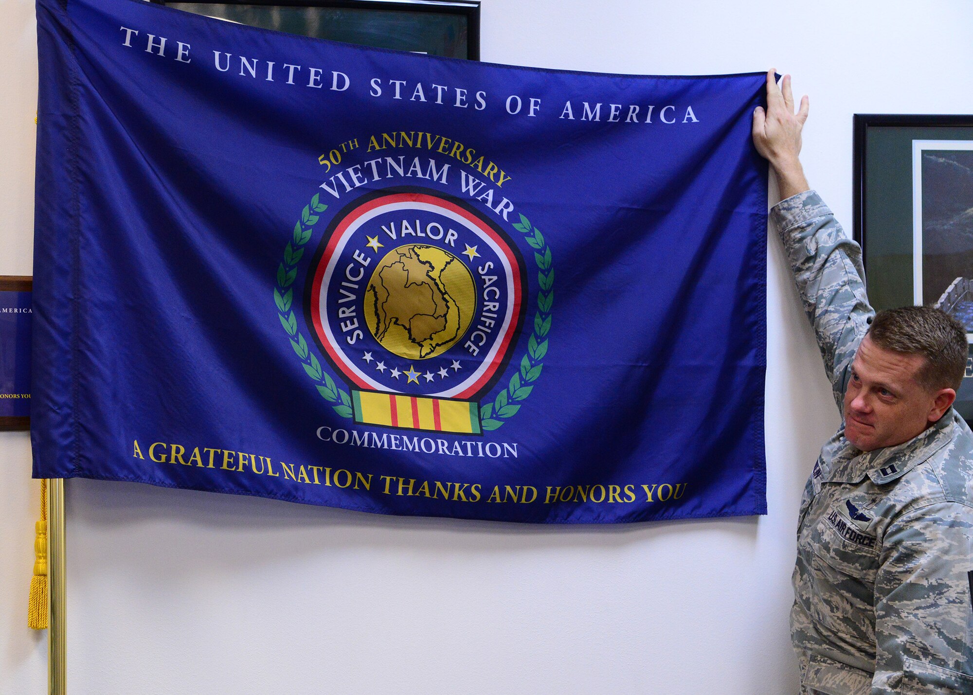 Chap. (Capt.) Christopher Conklin, 341st Missile Wing chaplain, unveils the 50th Anniversary Vietnam War commemoration flag Nov. 8 at the Malmstrom commissary. The event was held to honor the 50th anniversary of the Vietnam War and recognized the efforts made by U.S. service members during the war, which lasted for 16 years. (U.S. Air Force photo/Airman 1st Class Collin Schmidt)  