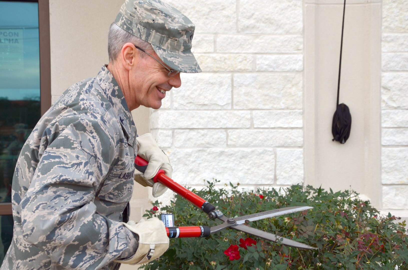 Brig. Gen. Bob LaBrutta, Joint Base San Antonio and 502nd Air Base Wing commander, prunes the bushes in front of building 247, the 502nd Air Base Wing headquarters, during Pride Day. (Photo by Lori Newman, JBSA-Fort Sam Houston Public Affairs)