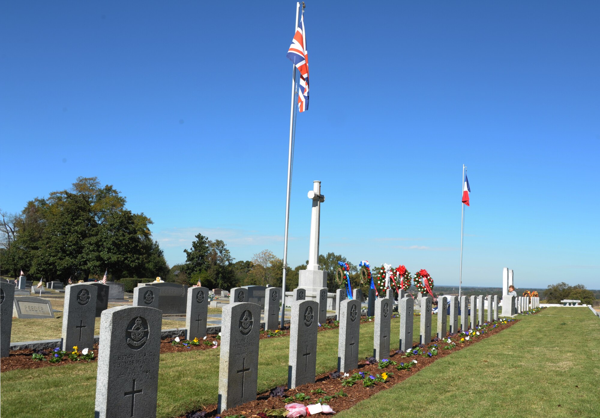 The Flags of Britain and France fly above the graves of French and British soldiers during a Remembrance Day Ceremony hosted at Oakwood Cemetery, Montgomery, Ala., by officers of the Royal Air Force and French air force, attending professional military education courses at Maxwell Air Force Base. The international officers hold a special annual memorial service at the graves of 78 RAF and 20 FAF cadets, who died from training accidents in the southeast United States during World War II. (U.S. Air Force photo by Staff Sgt. Gregory Brook)