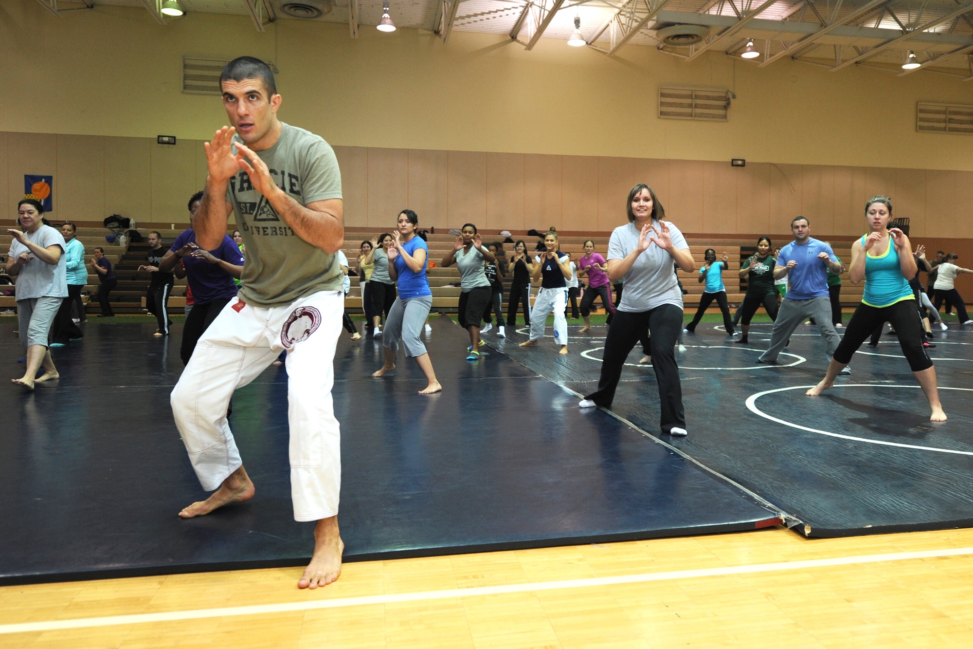 Rener Gracie, Gracie Academy Women Empowered self-defense seminar instructor, demonstrates a combat base pose as Team Malmstrom members follow. The weeklong self-defense seminar trained nearly 100 participants to become certified instructors. (U.S. Air Force photo/Senior Airman Katrina Heikkinen)