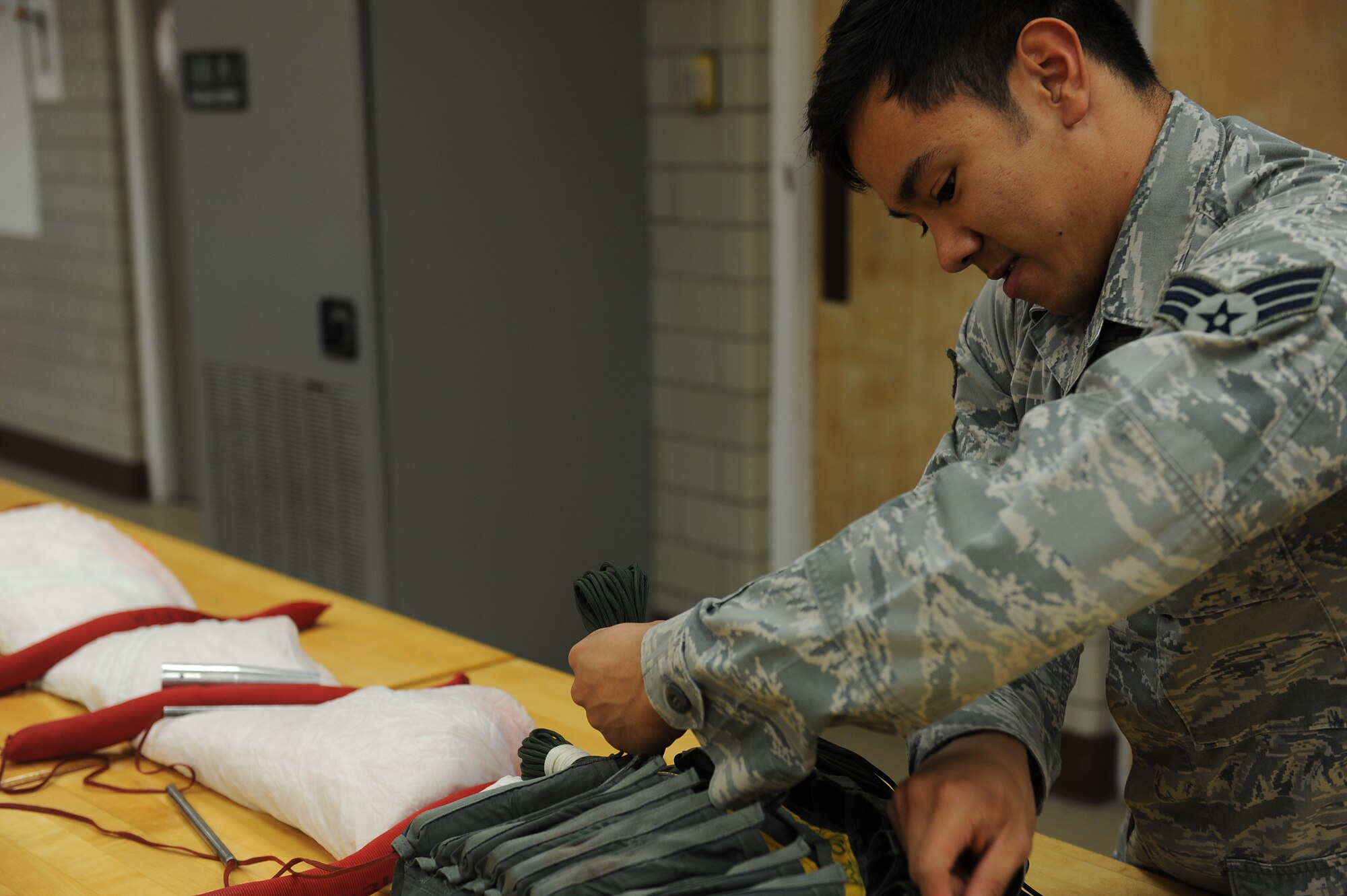 Senior Airman Ian Carrion, an air crew flight equipment journeyman with the 5th Operations Support Squadron here, carefully threads the lines of a parachute through an individual sized backpack. This parachute is assigned to a crew member of a B-52 Stratofortress and is used in case of emergency, requiring maximum attention to detail by the Airman. (U.S Air Force photo/Airman 1st Class Lauren Pitts)