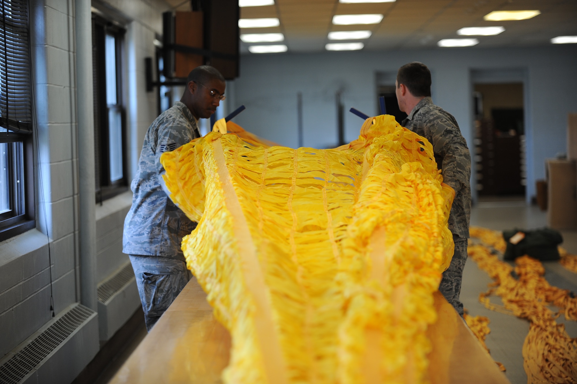 Staff Sgt. John J. Williams and Airman 1st Class Matthew Stelling, air crew flight equipment craftsman and apprentice with the 5th Operations Support Squadron at Minot Air Force Base, work on packing the drag parachute for a B-52H Stratofortress. The 90-foot parachute weighs approximately 200 pounds when fully packed and deploys as an aircraft lands, helping to slow down the aircraft on the runway. (U.S Air Force photo/Airman 1st Class Lauren Pitts)