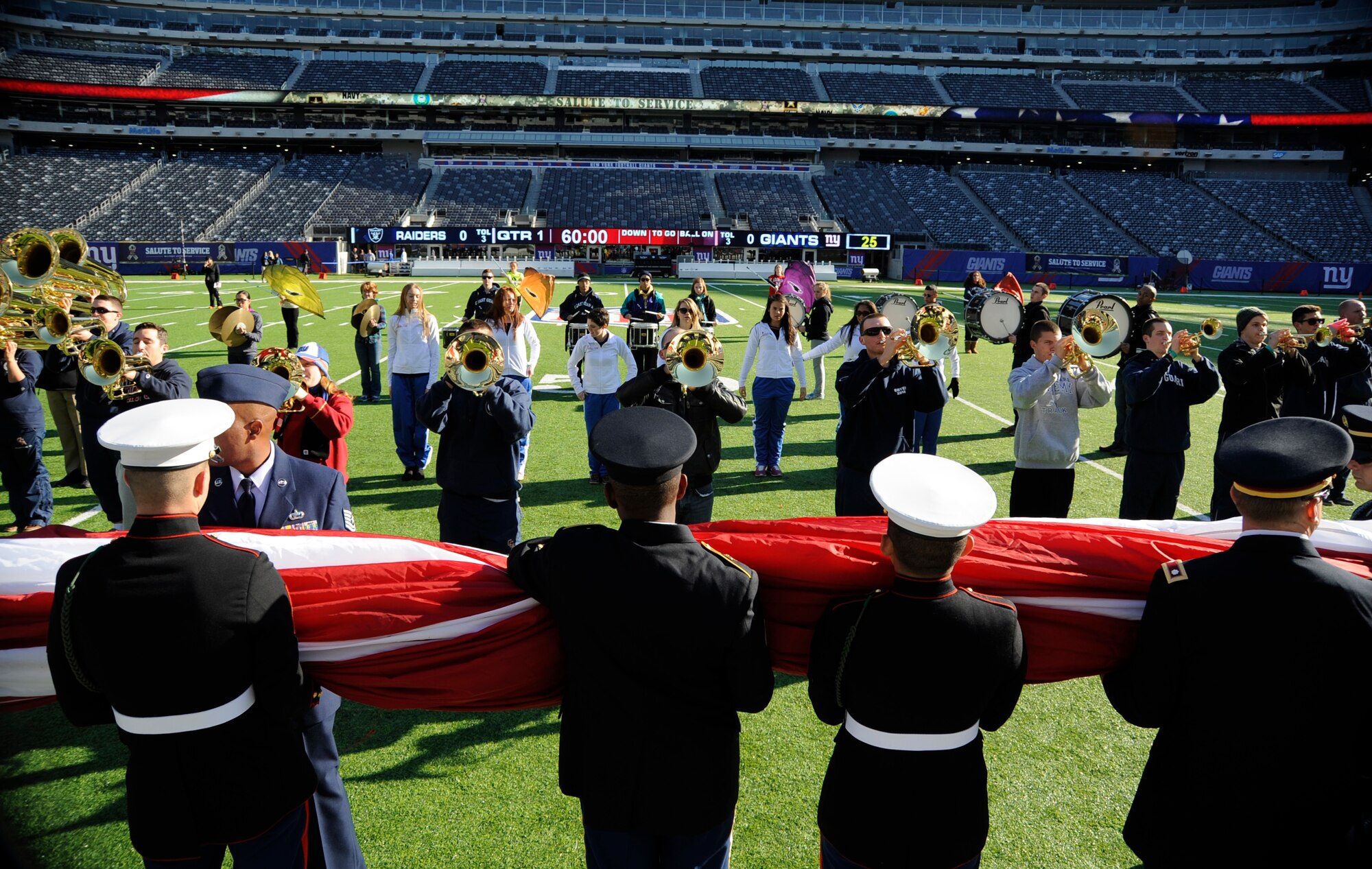 Joint Base McGuire-Dix-Lakehurst Airmen and other service members stand ready to unfurl an American Flag prop as the U.S. Coast Guard Academy band plays during practice for the New York Giant football pre-game show Nov. 10, 2013, at MetLife Stadium in East Rutherford, N.J. More than 125 service members participated in New York Giants pre-game show as part of Military Appreciation Day. (U.S. Air Force photo by Tech. Sgt. Darrell Dean/Released)