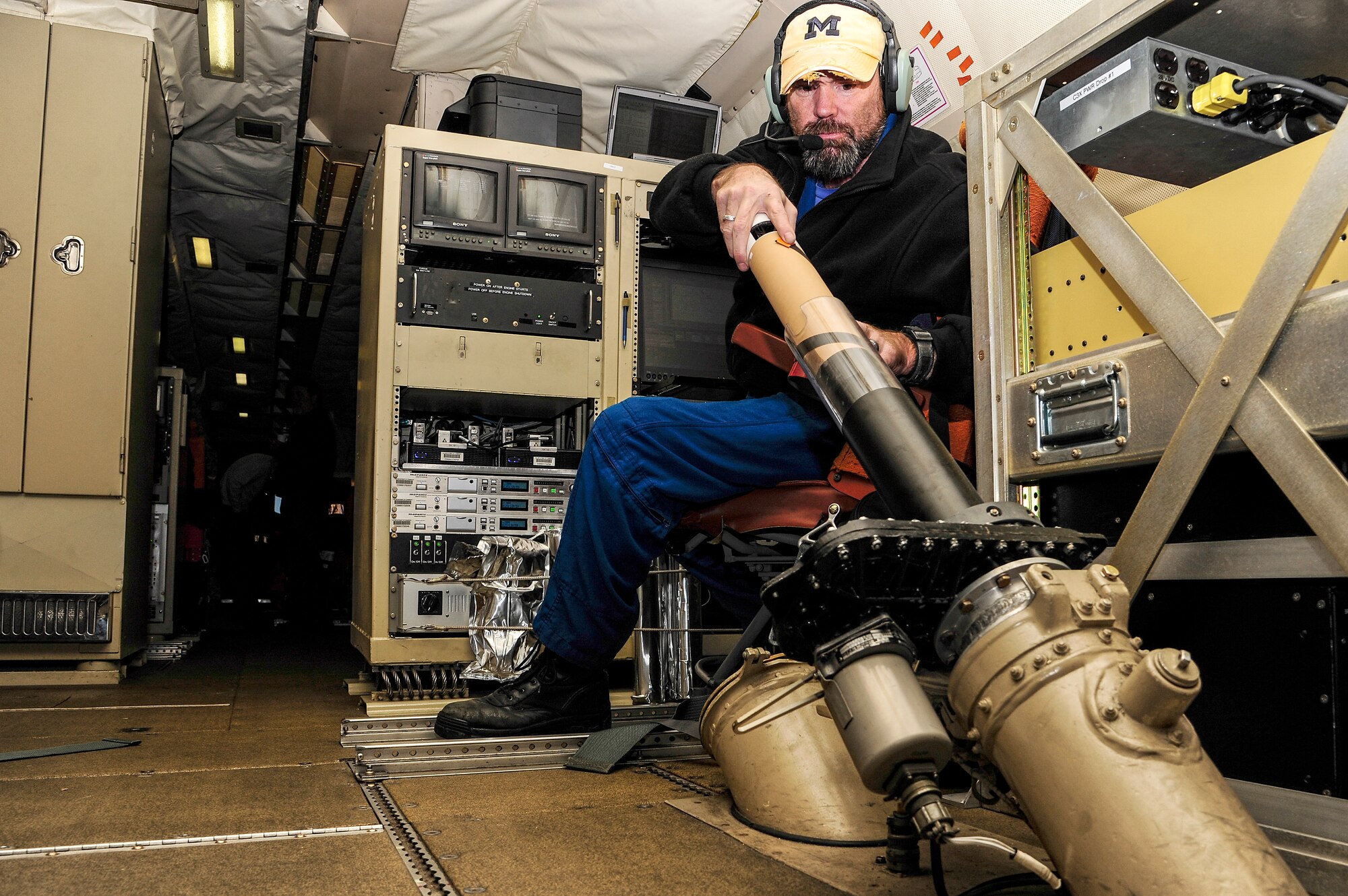 Bill Olney, National Oceanic and Atmospheric Administration avionics technician, loads a sensor into a drop tube during a flight over the Chukchi Sea Oct. 30, 2013. The sensors detect different air qualities, including pressure, temperature and relative humidity. (U.S. Air Force photo by Senior Airman Zachary Perras/Released)