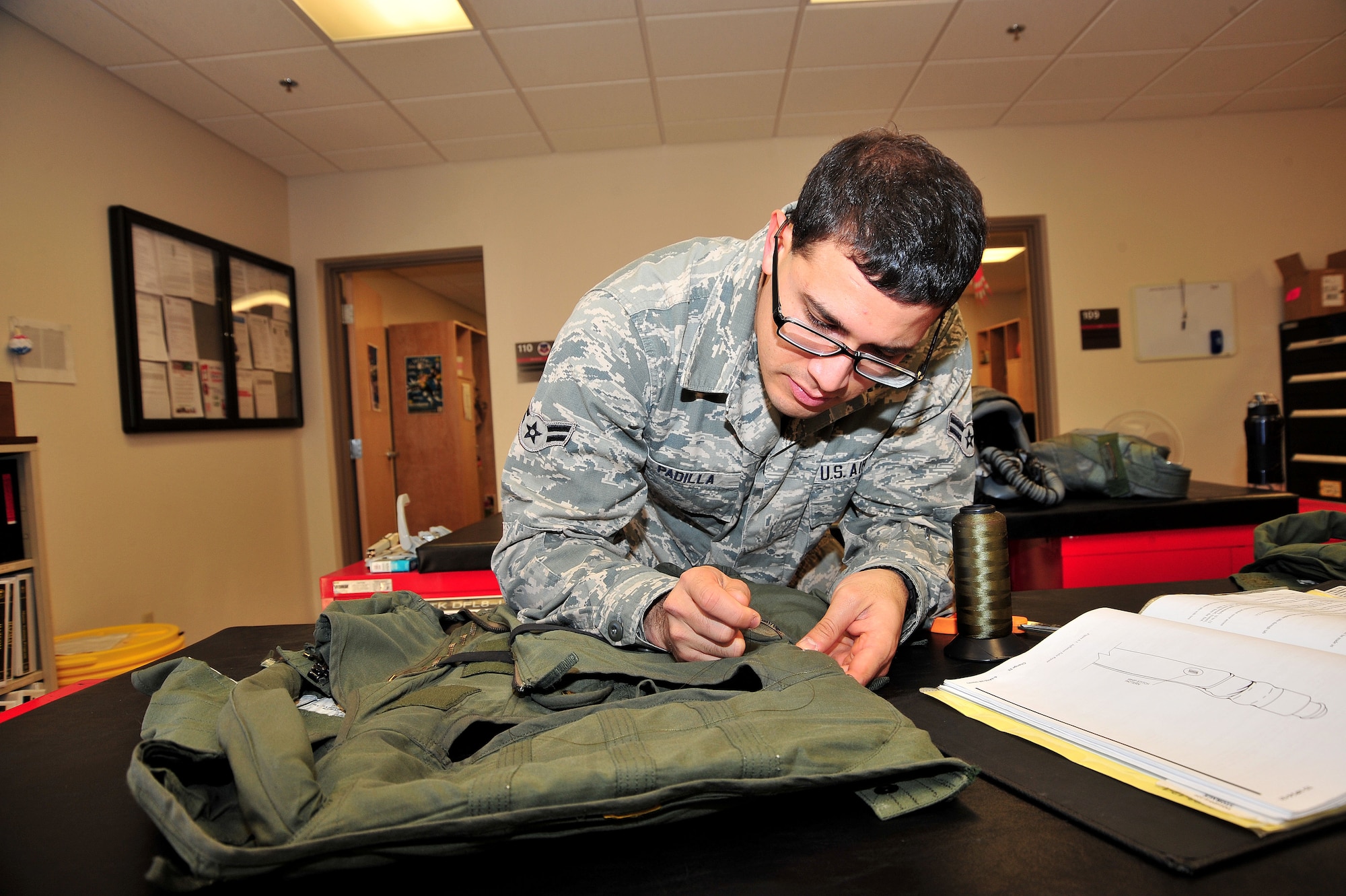 U.S. Air Force Airman 1st Class Jose Padilla, 355th Operations Support Squadron air crew flight equipment technician, repairs small holes and tears in a gravity suit at Davis-Monthan Air Force Base, Ariz., Nov. 7, 2013. Aside from repairing holes, padilla is also for flight equipment such as helmts oxygen masks, parachutes, floatation devices, survival kits, night vision goggles, and many other types of flight equipment.(U.S. Air Force photo by Senior Airman Josh Slavin/Released)