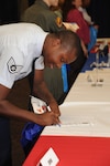 Staff Sgt. Terrence White-Ballard, 359th Aerospace Medical Squadron medical technician, signs a roster during the Newcomer’s Brief Information Fair at the Joint Base San Antonio Randolph Military and Family Readiness Center. (U.S. Air Force photo by Airman 1st Class Kenna Jackson)