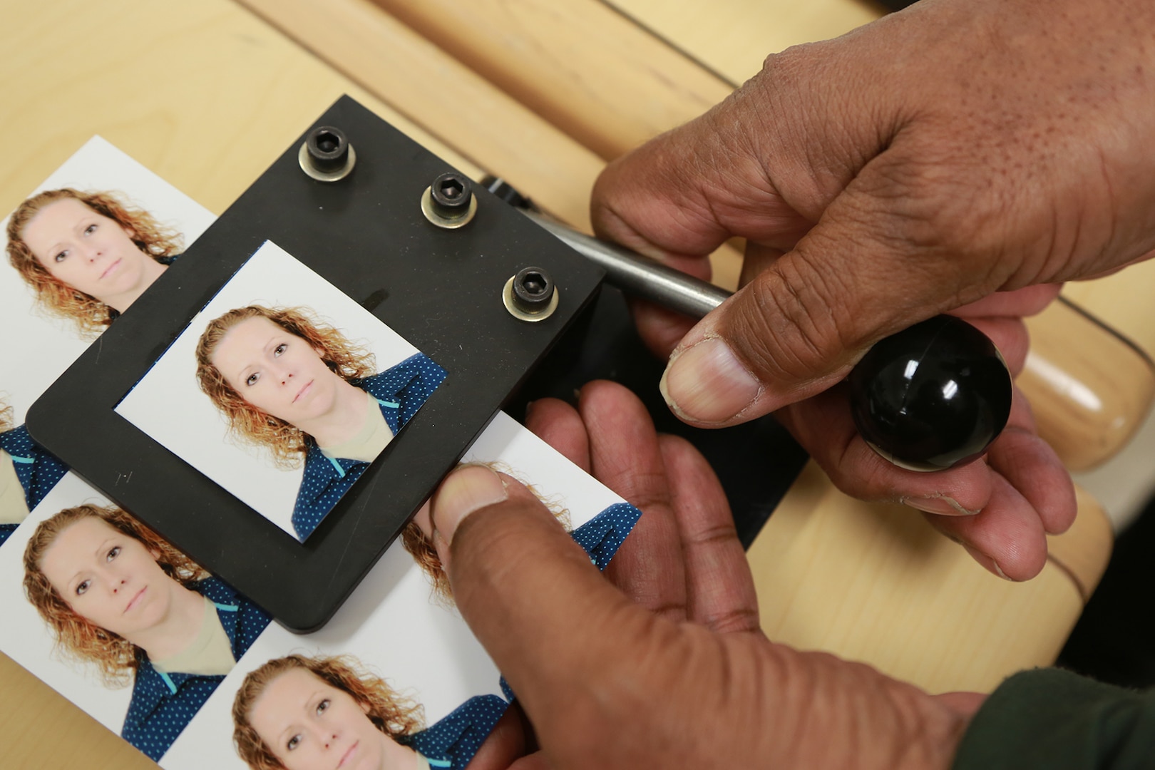 Passport photos are cut into the required measurements by a 502nd Air Base Wing photographer prior to customer delivery at Joint Base San Antonio-Lackland. Active-duty members and civilians who require passport photos must have an authorized agent at their location’s passport office sign a work order form before scheduling a passport photo appointment. (U.S. Air Force photo by Joshua Rodriguez)