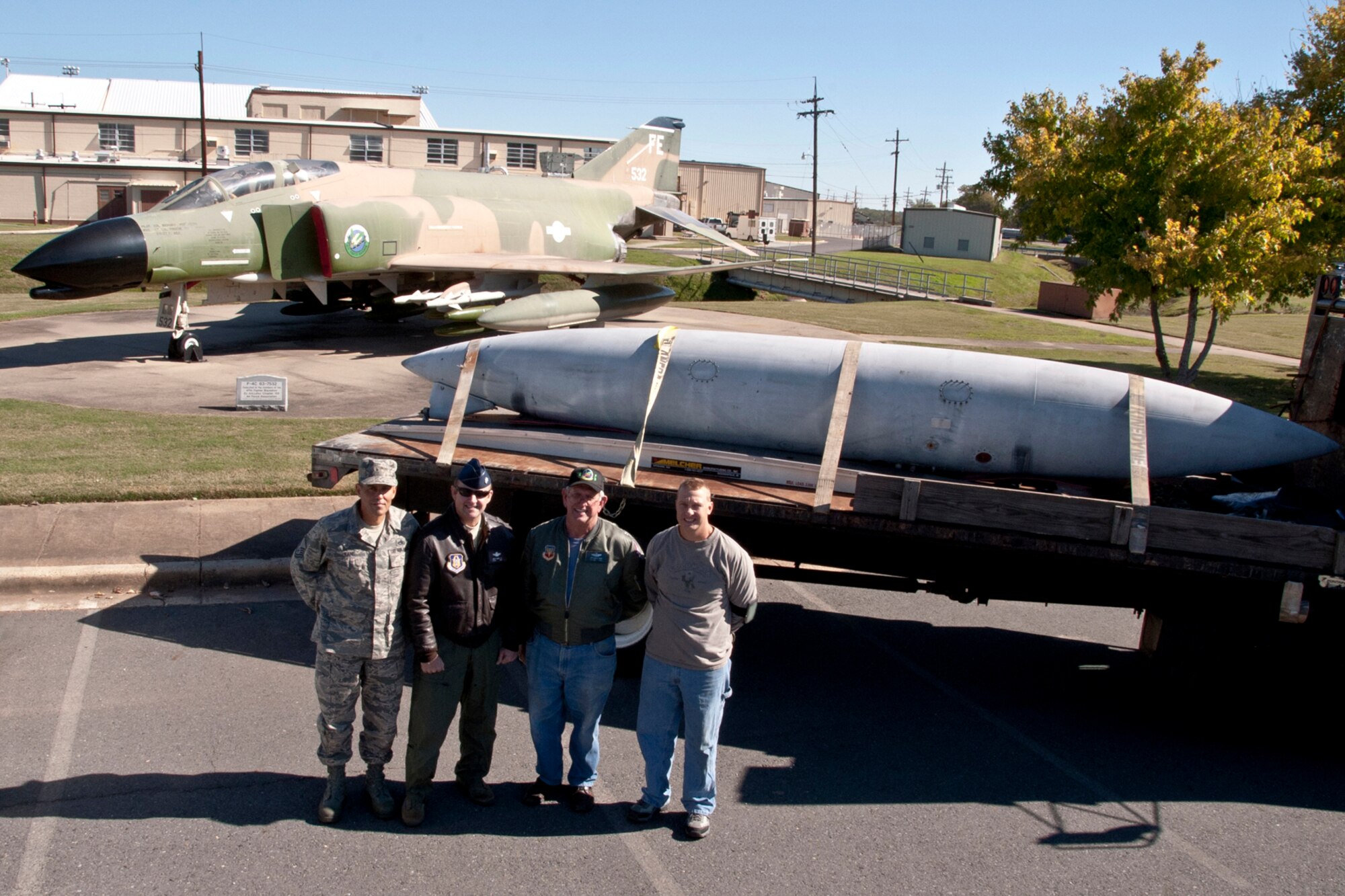 Master Sgt. John Kane, electronic environmental systems technician, 307th Maintenance Squadron, Lt. Col. James Marks, A-10 Thunderbolt II pilot, Retired U.S. Air Force Reserve Capt. Steve Dean and Master Sgt. Eric Swaim, aircraft hydraulic systems mechanic, 307 MXS, pose for a photo alongside a flatbed truck loaded with an F-4 Phantom fuel tank destined for Gilmer, Texas, at Barksdale Air Force Base, La., Nov. 13, 2013. The 600-gallon drop tank from the F-4 Phantom days of the 47th Fighter Squadron, which until 2011 was part of the 917th Wing at Barksdale, will soon be part of a prime museum display at the Flight of the Phoenix Aviation Museum at Fox Stephens Field in Gilmer. In July 1965, the 47 FS deployed to Ubon Royal Thai Air Force Base, Thailand, and compiled 1,743 combat missions over Southeast Asia. This fuel tank very likely flew on combat missions during the Vietnam War. (U.S. Air Force photo illustration by Master Sgt. Jeff Walston)