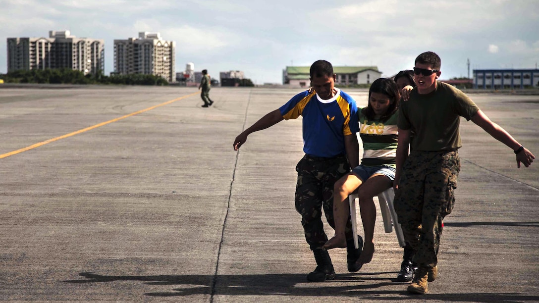 Lance Cpl. John Robertson, right, a landing support specialist with the 3rd Marine Expeditionary Brigade, and members of the Armed Forces of the Philippines (AFP) assist a civilian displaced by Typhoon Haiyan as part of Operation Damayan at Villamor Air Base, Nov. 14. Typhoon Haiyan has impacted more than 4.2 million people across 36 provinces in the Philippines according to the government's National Disaster Risk Reduction and Management Council. (U.S. Marine Corps photo by Lance Cpl. Anne K. Henry/RELEASED)