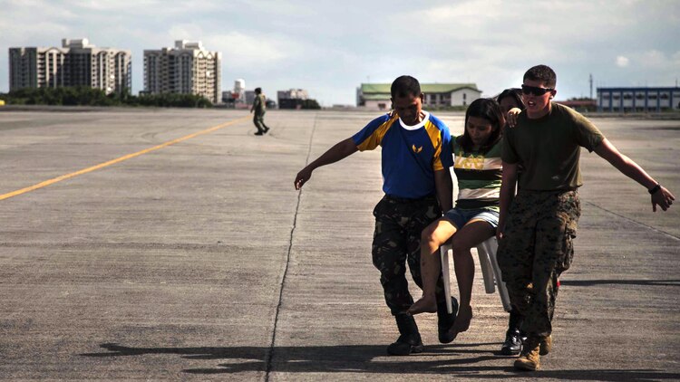 Lance Cpl. John Robertson, right, a landing support specialist with the 3rd Marine Expeditionary Brigade, and members of the Armed Forces of the Philippines (AFP) assist a civilian displaced by Typhoon Haiyan as part of Operation Damayan at Villamor Air Base, Nov. 14. Typhoon Haiyan has impacted more than 4.2 million people across 36 provinces in the Philippines according to the government's National Disaster Risk Reduction and Management Council. (U.S. Marine Corps photo by Lance Cpl. Anne K. Henry/RELEASED)