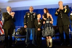 Secretary of the Army John McHugh, left, and Army Chief of Staff Gen. Ray Odierno, right, applaud as the Flores family is awarded the 2013 Association of the United States Army Family of the Year at the organization's annual meeting and exposition in Washington, D.C., Oct. 21, 2013. The family members are 1st Sgt. Tommy Flores, his wife Laura, daughter Zanayah, 12, and son Carlos, 10.