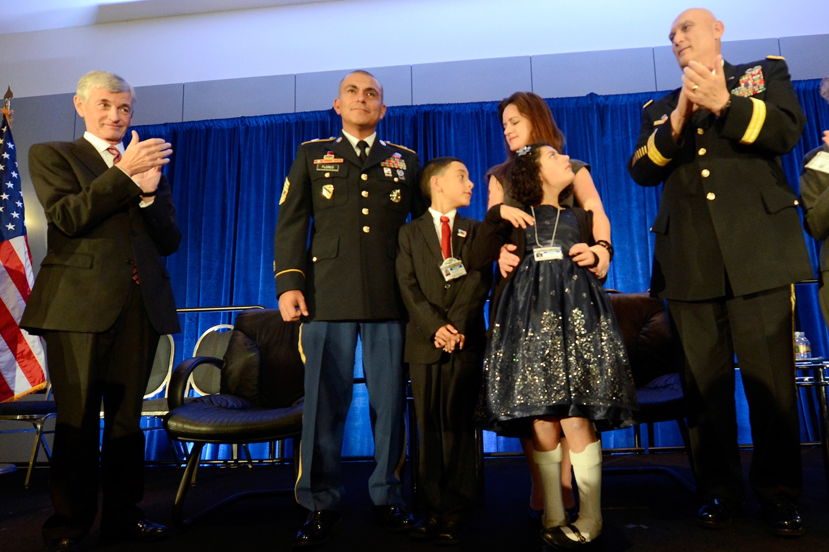 Secretary of the Army John McHugh, left, and Army Chief of Staff Gen. Ray Odierno, right, applaud as the Flores family is awarded the 2013 Association of the United States Army Family of the Year at the organization's annual meeting and exposition in Washington, D.C., Oct. 21, 2013. The family members are 1st Sgt. Tommy Flores, his wife Laura, daughter Zanayah, 12, and son Carlos, 10.