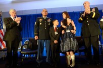 Secretary of the Army John McHugh, left, and Army Chief of Staff Gen. Ray Odierno, right, applaud as the Flores family is awarded the 2013 Association of the United States Army Family of the Year at the organization's annual meeting and exposition in Washington, D.C., Oct. 21, 2013. The family members are 1st Sgt. Tommy Flores, his wife Laura, daughter Zanayah, 12, and son Carlos, 10.
