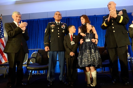 Secretary of the Army John McHugh, left, and Army Chief of Staff Gen. Ray Odierno, right, applaud as the Flores family is awarded the 2013 Association of the United States Army Family of the Year at the organization's annual meeting and exposition in Washington, D.C., Oct. 21, 2013. The family members are 1st Sgt. Tommy Flores, his wife Laura, daughter Zanayah, 12, and son Carlos, 10.