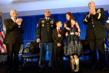 Secretary of the Army John McHugh, left, and Army Chief of Staff Gen. Ray Odierno, right, applaud as the Flores family is awarded the 2013 Association of the United States Army Family of the Year at the organization's annual meeting and exposition in Washington, D.C., Oct. 21, 2013. The family members are 1st Sgt. Tommy Flores, his wife Laura, daughter Zanayah, 12, and son Carlos, 10.