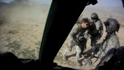 Capt. William Swenson, left, assists severely wounded Sgt. 1st Class Kenneth Westbrook onto a UH-60 Black Hawk helicopter, Sept. 8, 2009, during the Battle of Ganjgal, in Afghanistan. Sgt. Marc Dragony, right, and Staff Sgt. Kevin Duerst, foreground holding an M4 carbine, from the California National Guard, assist.