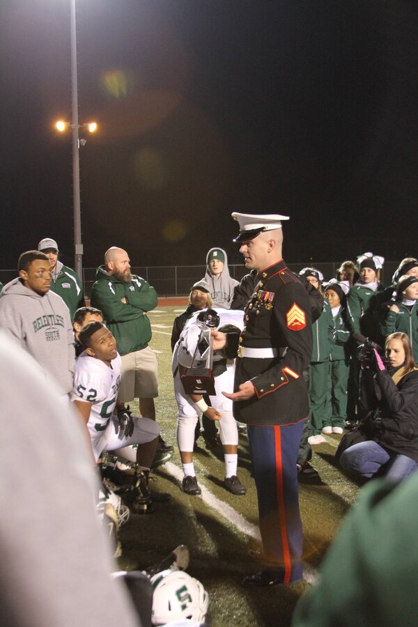 U.S. Marine Corps Sgt. Edward Alsip, an Ohio native and recruiter for Hagerstown Md., congratulates the Rebels in their 34-27 win over the Hubs at the North South Rivalry Game Nov. 8, 2013. Alsip presented them with a Marine Corps trophy donated by Chief Warrant Officer 3 Cole Barnhart, a Hagerstown native and recruiting support officer. Alsip was able to speak about leadership and heart used in football, which can parallel a career in the U.S. Marine Corps. (U.S. Marine Corps photo by Sgt. Amber Williams/Released)