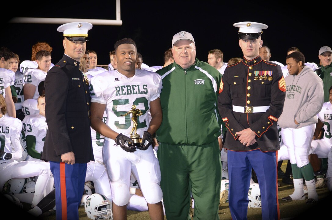 U.S. Marine Corps Sgt. Edward Alsip, far right, an Ohio native and recruiter for Hagerstown Md., and Chief Warrant Officer 3 Cole Barnhart, far left, a Hagerstown native and recruiting support officer, congratulate the Rebels’ MVP Isaiah Smith and head coach Toby Peer Nov. 8, 2013.  The Rebels defeated North Hagerstown High School 34-27 in the North South Rivalry Game. (courtesy photo by LeeAnn Barnhart)