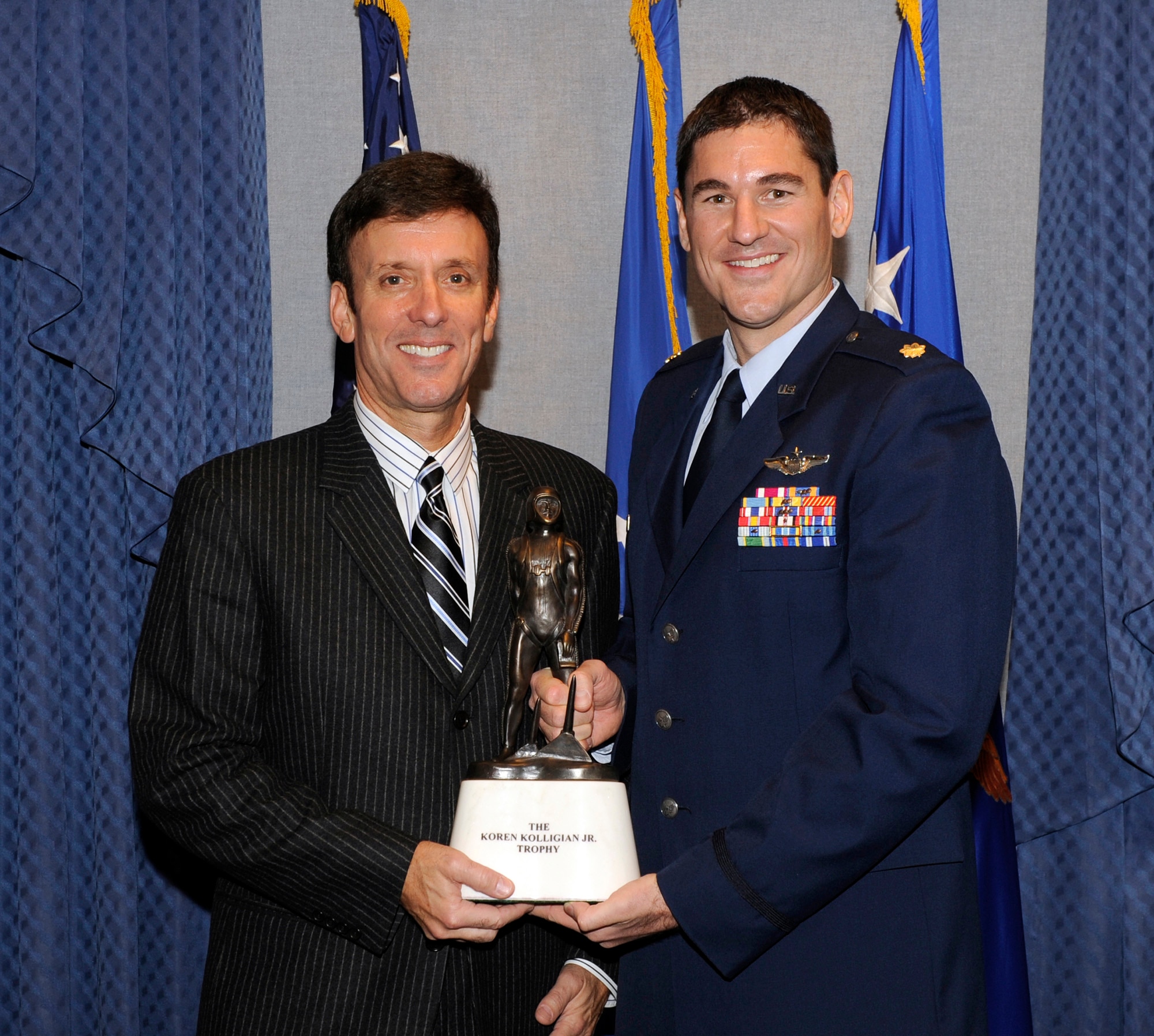 Cory Kolligian, representing the Kolligian family, congratulates Maj. Douglas Witmer, this year's recipient of the Kolligian trophy, during an award ceremony honoring Witmer  Nov. 14, 2013, in the Pentagon. Witmer is this year's recipient of the Koren Kolligian Jr. trophy for outstanding Airmanship.