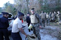 Marines and sailors with 2nd Medical Battalion, Combat Logistics Regiment 25, 2nd Marine Logistics Group load nonperishable items onto trucks halfway through a six mile hike aboard Camp Lejeune, N.C., Nov. 15, 2013. Service members were encouraged to fill their packs with up to 65 pounds of nonperishable food items, which they personally donated to less fortunate families within the battalion for the Thanksgiving and Christmas holidays. (U.S. Marine Corps photo by Lance Cpl. Shawn Valosin)