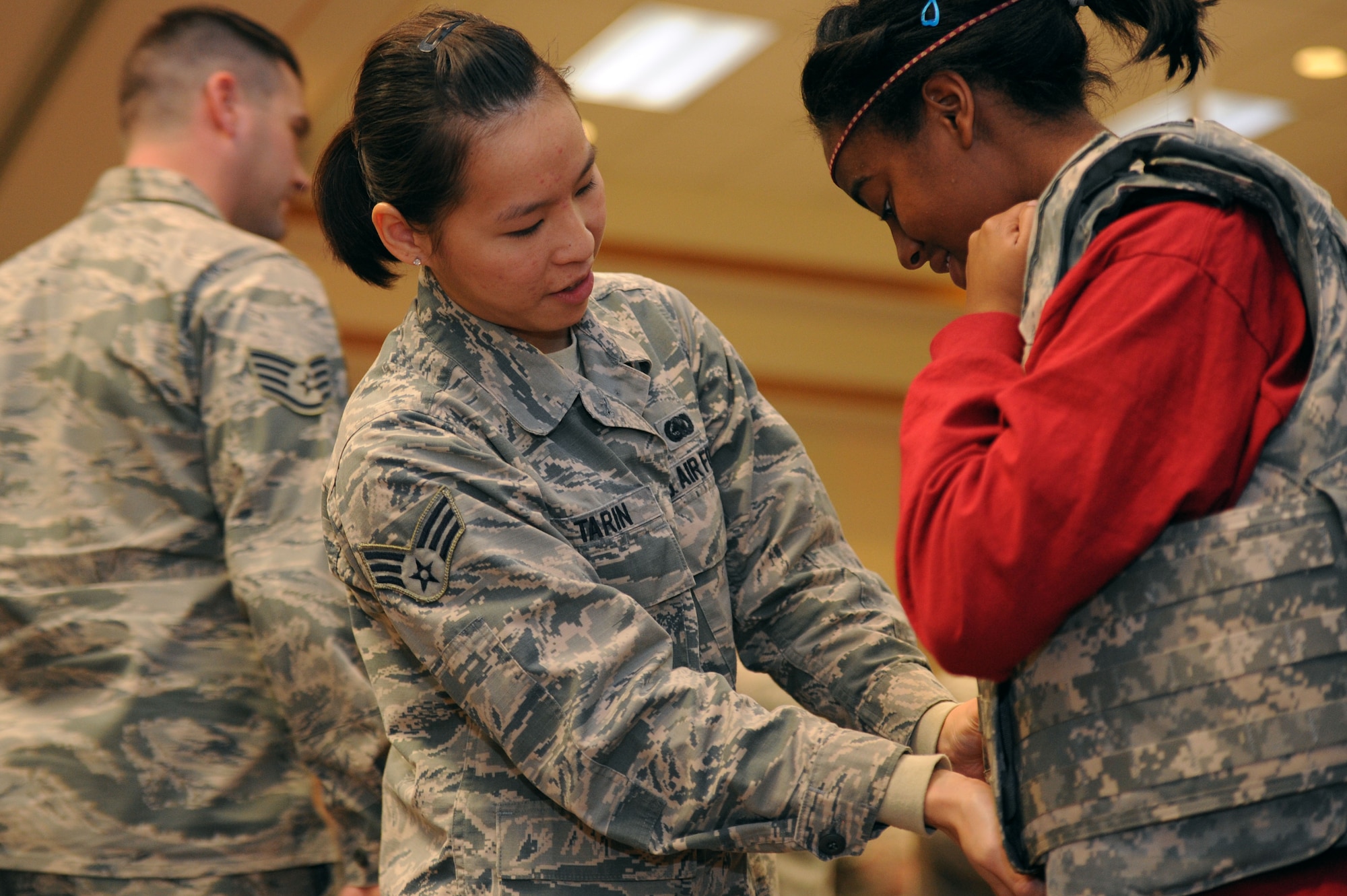 ALTUS AIR FORCE BASE, Okla. – U.S. Air Force Senior Airman Yookchan Tarin, 97th Logistics Readiness Squadron material management journeyman, helps a Junior Reserve Officers’ Training Corps high school student from Lawton, Okla. put on a tactical vest during a career fair at the Freedom Community Center Nov. 14, 2013. Yookchan and other Airmen from various units on base set up information booths and shared their expertise and knowledge of their jobs with the students. The career fair was held to highlight the Air Force mission and different Air Force specialty codes. (U.S. Air Force photo by Airman 1st Class Klynne Pearl Serrano/Released)