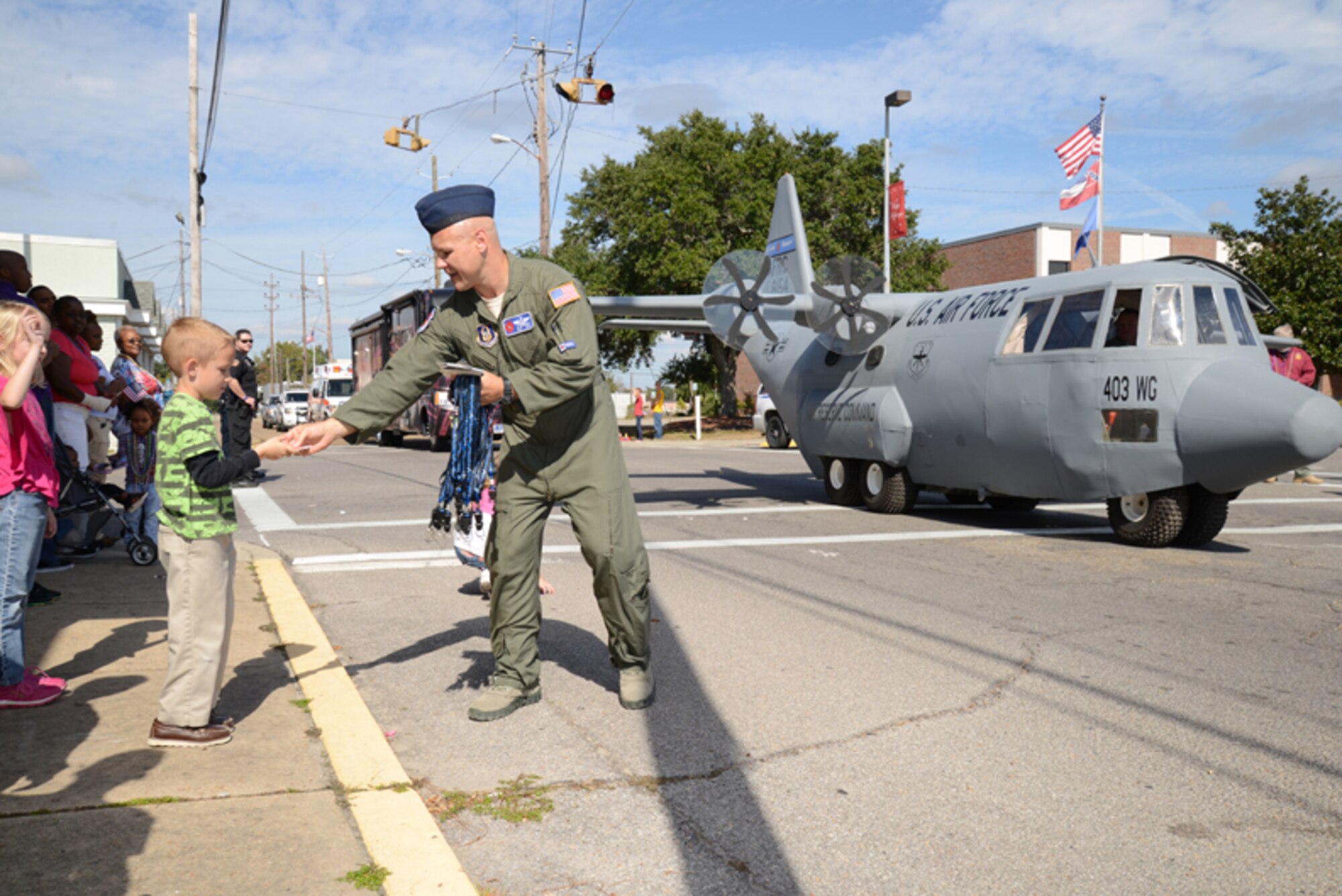 Master Sgt. Ed Scherzer, 53rd Weather Reconnaissance Squadron weather reconnaissance loadmaster, gives a Hurricane Hunter doubloon to a young spectator during the Biloxi Veterans Day parade Nov. 9. Members of the 403rd Wing from Keesler Air Force Base, Miss., guided Lil' Bill, a mock C-130J aircraft, down the road during the event. Hundreds of people turned out to view the procession of floats, bands and marching units to show their appreciation for members of the U.S. Armed Forces. (U.S. Air Force photo/Tech. Sgt. Ryan Labadens)