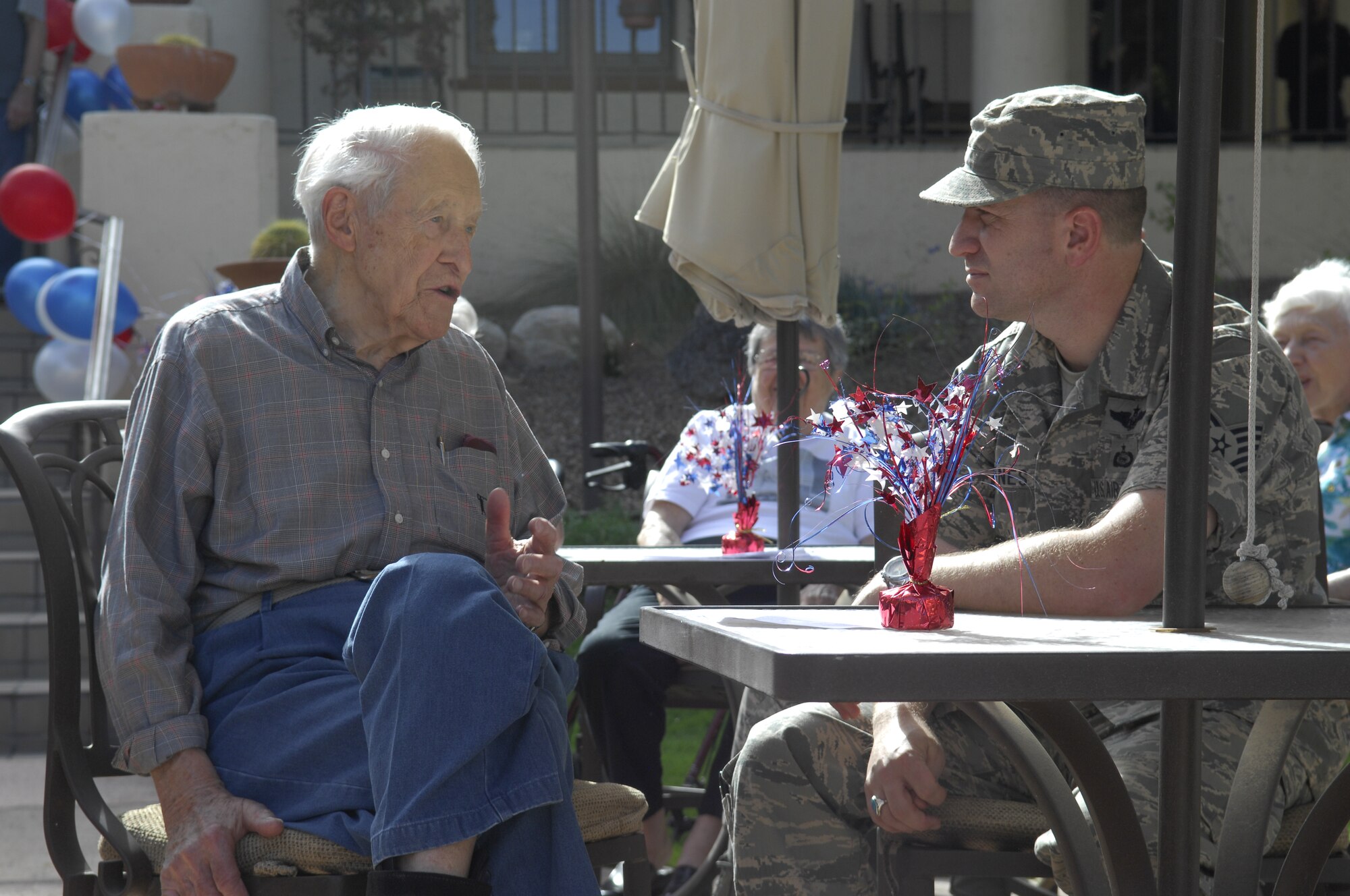 U.S. Air Force Tech Sgt. Roland Jones, 41st Electronic Combat Squadron mobility section chief, talks with a veteran during a luncheon hosted by Atria Bell Court Gardens Retirement Community in Tucson, Ariz., Nov. 13, 2013. Fifteen Airmen spent time talking to the veterans, learning about each other and the changes in the military over time.(U.S. Air Force Photo by Airman 1st Class Betty R. Chevalier/Released)